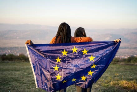 two people from behind holding a EU flag behind their backs