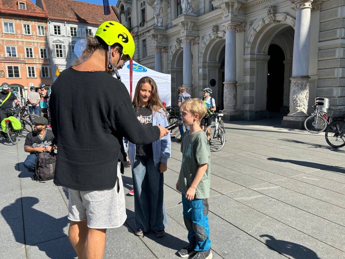 Ein Mann mit Radhelm interviewt einen Jungen vor dem Grazer Rathaus.