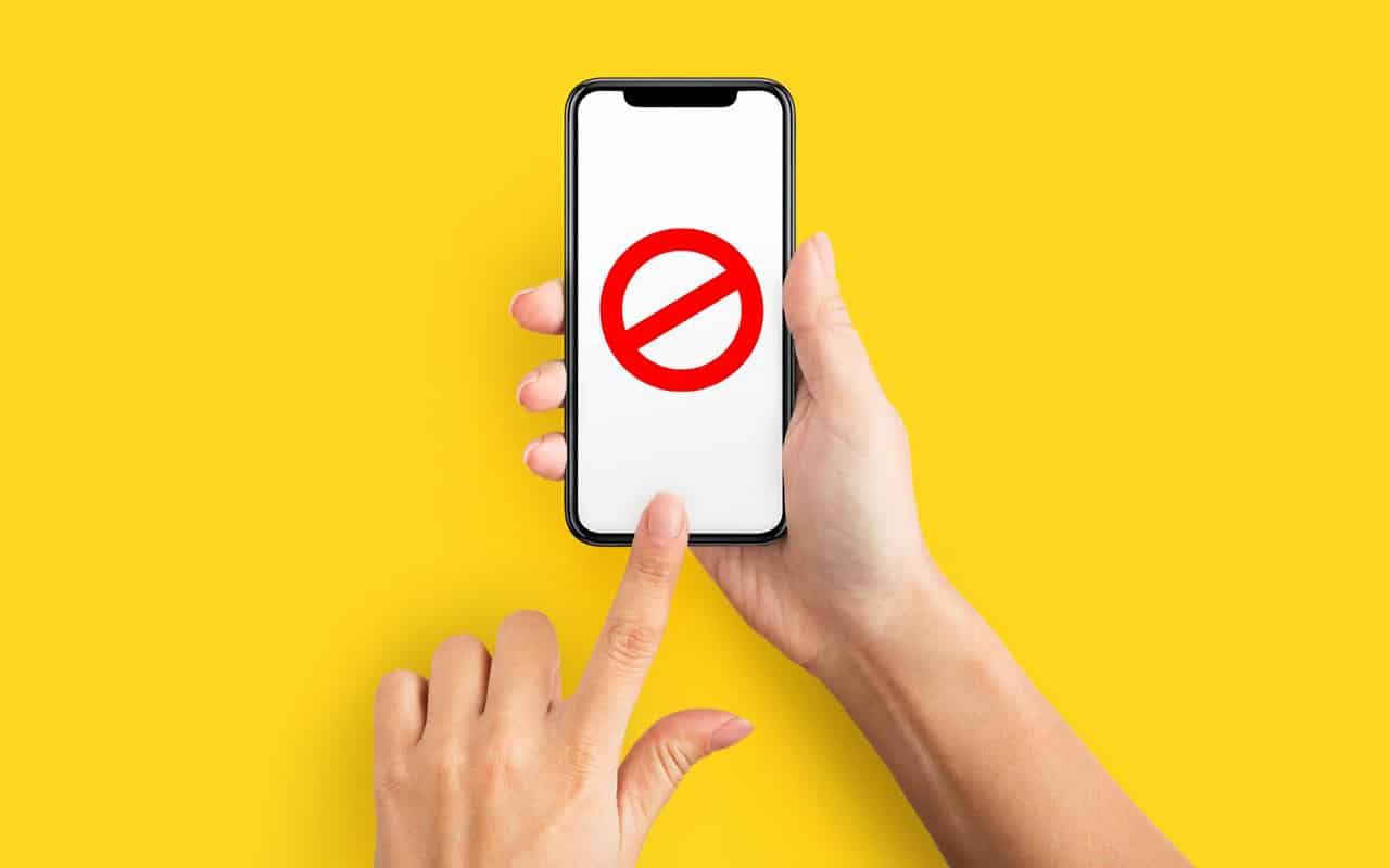Foto vom einem Smartphone auf gelbem Grund, wo ein Verbotszeichen aufscheint